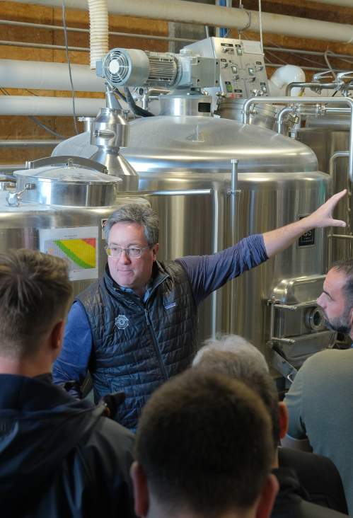 A group of people listening to a man speak inside a warehouse.