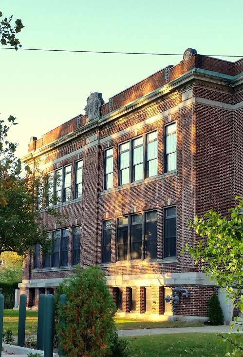 A brick building with trees in the foreground.