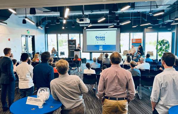 A room full of people looking at a presentation on a projector.